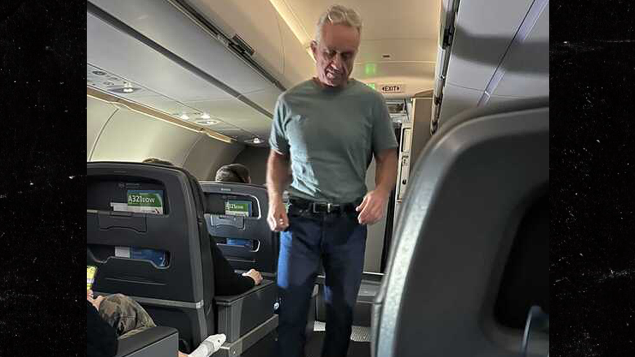 Robert F.  Kennedy Jr. percorre a piedi nudi il corridoio durante un volo di prima classe