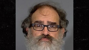 Michael Lewis is seen posing for a mugshot. He's wearing a white t-shirt and glasses.
