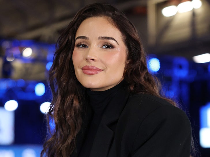 Olivia Culpo's pictured wearing a black jacket on top of a matching turtleneck sweater.