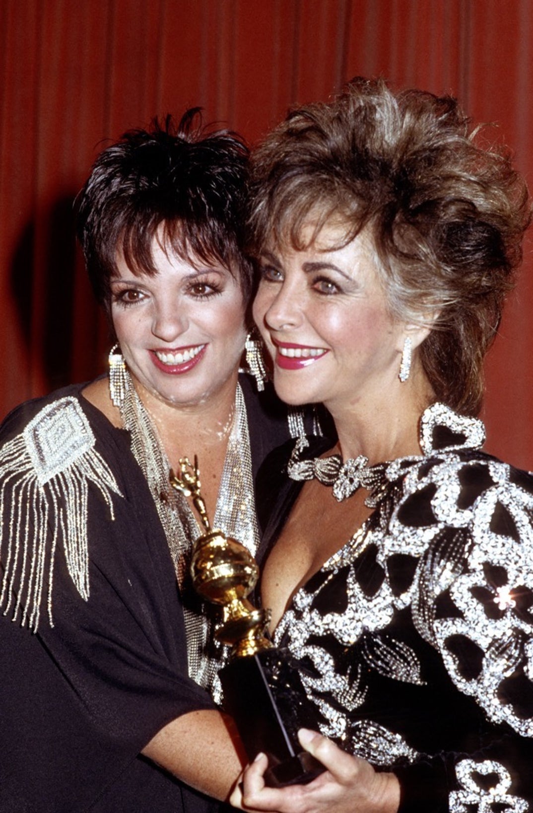 1985 --An iconic duo, Liza Minnelli embracing Elizabeth Taylor at the 42nd Annual Golden Globe Awards. Taylor is holding her Cecil B. DeMille Award for Lifetime Achievement.