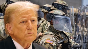 Donald Trump's looking concerned in front of a few National Guard members. He's wearing a black jacket, white shirt, and red tie.