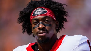 Zachariah Branch is seen suited up for a game. He's wearing a white, red, and black football jersey, and a red headband featuring the University of Georgia's logo.