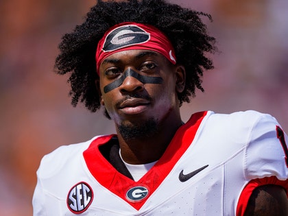 Zachariah Branch is seen suited up for a game. He's wearing a white, red, and black football jersey, and a red headband featuring the University of Georgia's logo.