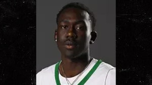 A young man wearing a white-and-green Adidas basketball jersey with the text 