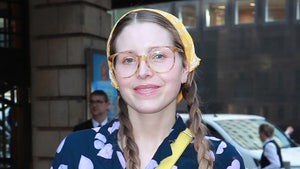 Jessie Cave is seen while leaving an event. She's wearing a blouse with several hearts on its front portion, a yellow purse and a near-matching bandana.