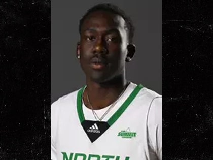 A young man wearing a white-and-green Adidas basketball jersey with the text 