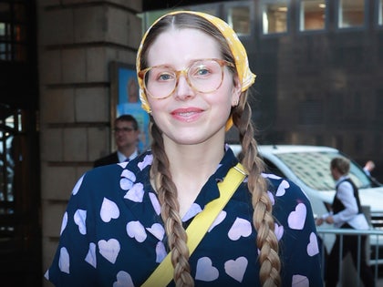 Jessie Cave is seen while leaving an event. She's wearing a blouse with several hearts on its front portion, a yellow purse and a near-matching bandana.