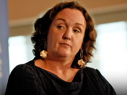 Katie Porter's looking upset at an event. She's wearing a black dress.