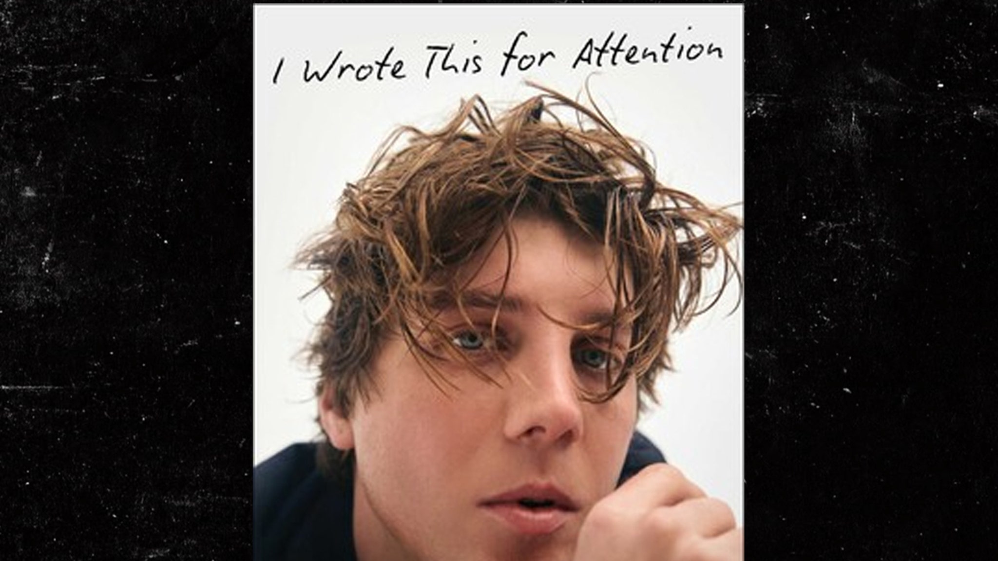 The image shows a close-up portrait of a young person with tousled, messy brown hair partially covering their forehead and eyes. Their expression is neutral to pensive, with slightly parted lips and a hand resting near their chin. The background is plain white, and at the top of the image, handwritten text reads, 'I Wrote This for Attention.'