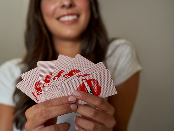 Woman holds Scandalous playing cards