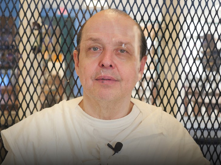 Robert Roberson is seen in a prison. He's wearing a white t-shirt underneath a white jumpsuit, and he has a small microphone attached to his chest.