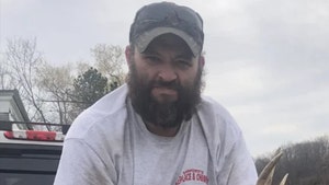 Thomas Jacob Sanford is seen sitting on the back of a truck. He's wearing a gray t-shirt and has a pair of sunglasses perched on top of his cap.
