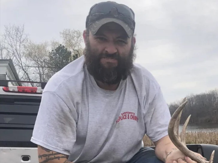 Thomas Jacob Sanford is seen sitting on the back of a truck. He's wearing a gray t-shirt and has a pair of sunglasses perched on top of his cap.