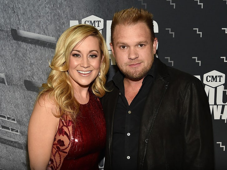 Kellie Pickler and Kyle Jacobs are seen at an awards show. She's wearing a red dress, while he's wearing a black button-up shirt and a matching jacket.