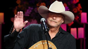 Alan Jackson's seen performing at a concert. He's wearing a black button-up shirt and a beige ten-gallon hat.