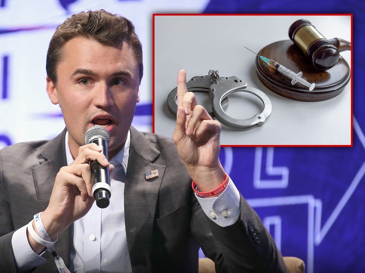 Charlie Kirk's seen speaking into a microphone next to a graphic of a pair a handcuffs and a syringe. He's wearing a gray coat with an American flag pin, as well as a light blue shirt.