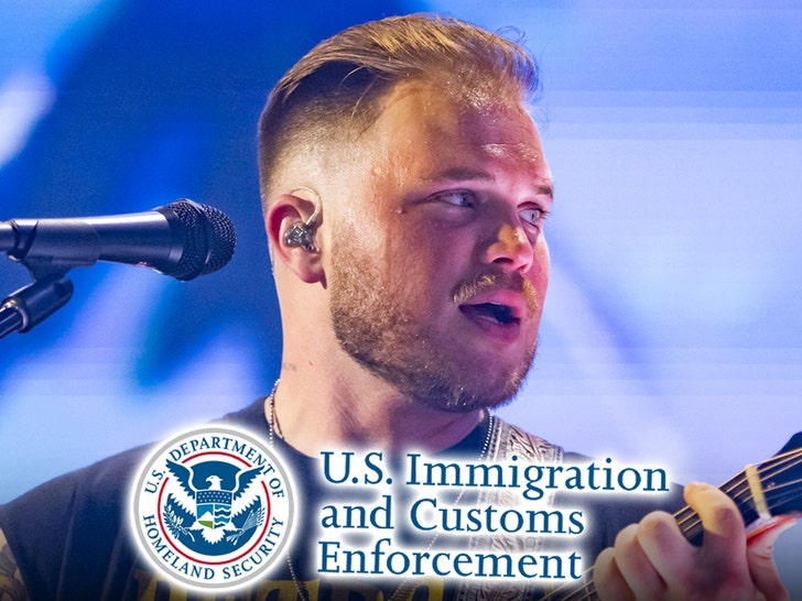 Zach Bryan's performing behind the logo for ICE. He's wearing a black t-shirt.