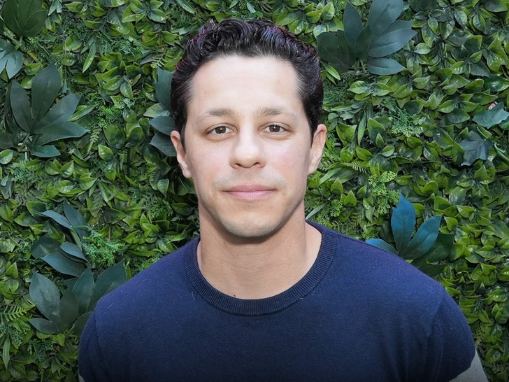 David Del Rio is seen posing for a photo. He's wearing a dark blue crewneck sweater.