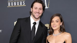 Josh Allen is wearing a suit and tie while standing next to his wife Hailee Steinfeld, who's wearing a black dress and several pieces of jewelry as they attend the NFL Honors cermony.
