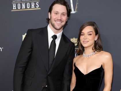 Josh Allen is wearing a suit and tie while standing next to his wife Hailee Steinfeld, who's wearing a black dress and several pieces of jewelry as they attend the NFL Honors cermony.