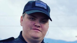 Garry Chapman is smiling while posing for a photo. He's wearing a black vest and a matching shirt with a Blue Lives Matter patch on its front.