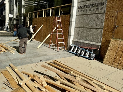 People Covering A Store With Wood Boards