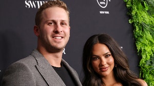 Jared Goff is seen standing next to his wife Christen. He's wearing a patterned jacket and black t-shirt, while she's wearing a gold-colored dress.