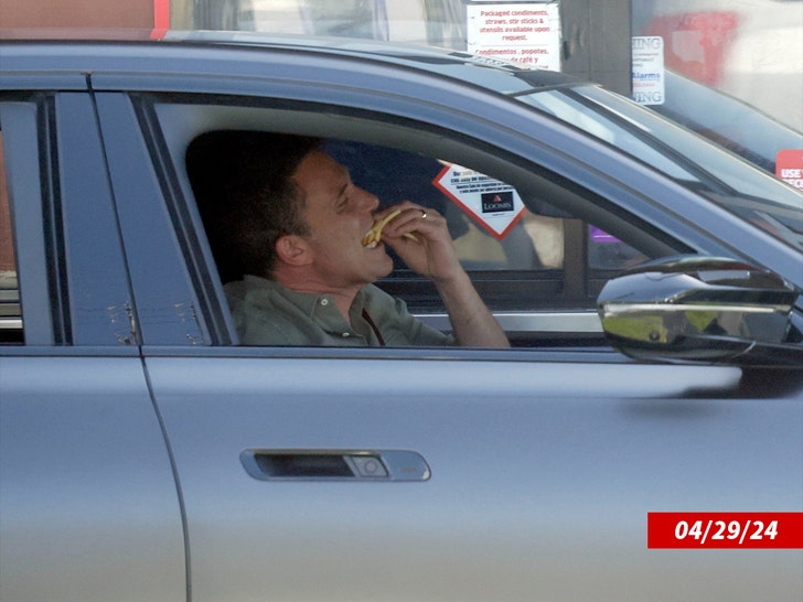 Ben Affleck eating french fries inside of a car.