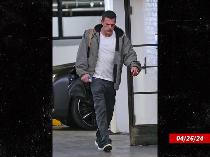 Ben Affleck walking in a white t-shirt, dark pants, and a jacket, with a bag over his shoulder, on the day of his separation from Jennifer Lopez.