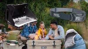 Family Sitting By A Fire Surrounded By Camping Gear