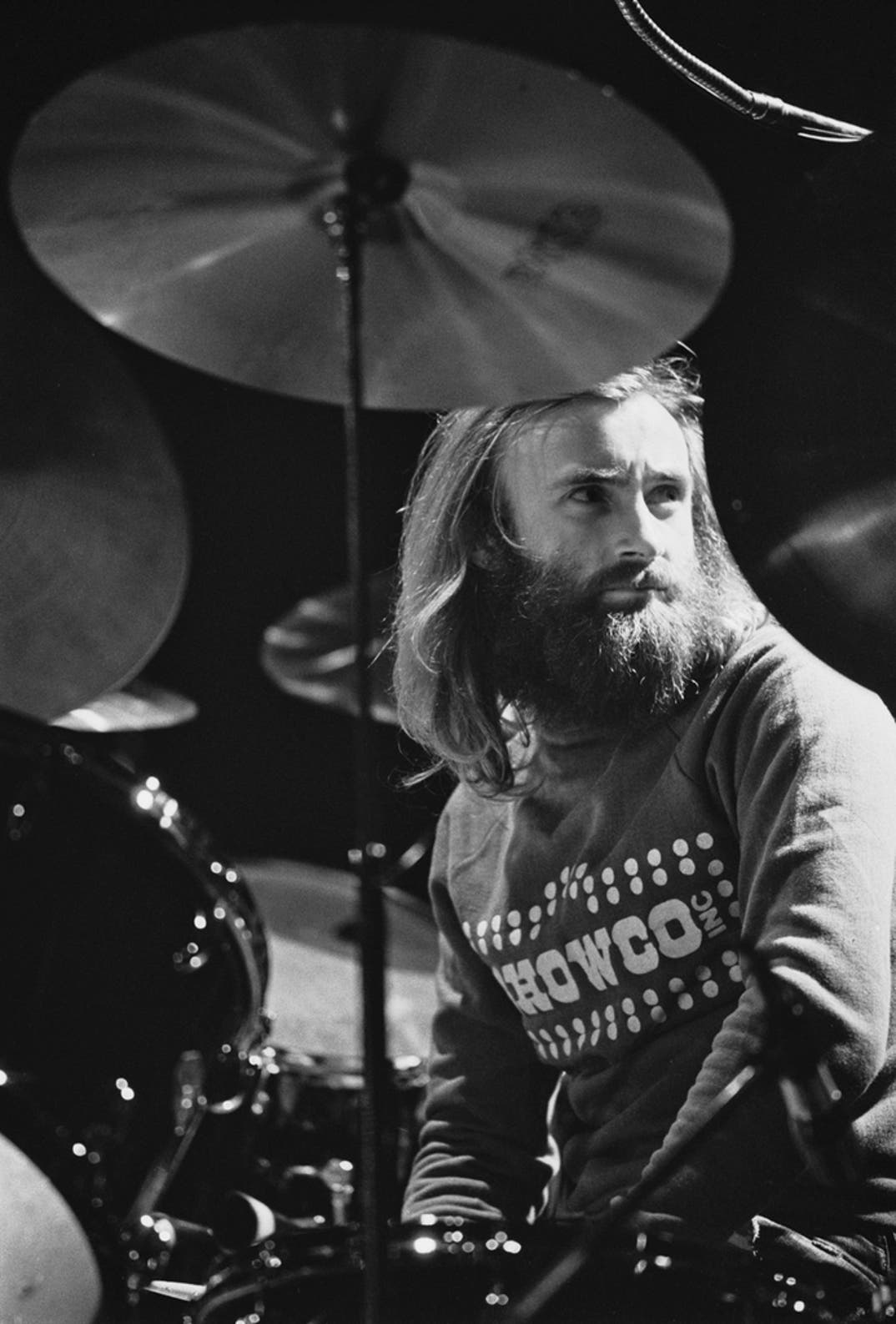 Phil Collins, drummer and singer with British rock band Genesis, takes a break behind his drum kit while rehearsing at the Rainbow Theatre, London, UK, in January 1977.