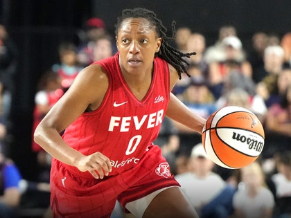 Kelsey Mitchell is seen during an Indiana Fever game. She's wearing a red-and-white jersey, as well as matching athletic shorts.