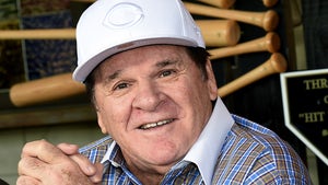 Pete Rose smiling while wearing a shirt with contrast white cuffs and collar, and a white Cincinnati Reds hat.