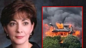 Judge Diane Goodstein is seen next to a photo of her burning home in South Carolina. She's wearing a black jacket.