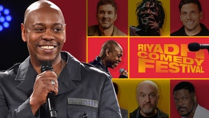 Dave Chappelle is smiling next to a poster for the Riyadh Comedy Festival.