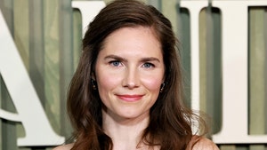 Amanda Knox is seen at what appears to be an awards show. She's wearing a multicolored dress, and her brunette hair is falling onto her shoulders.