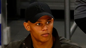 David Andrew Armstrong is seen looking out during an event. He's wearing a black jacket, as well as a matching t-shirt and Yankees cap.