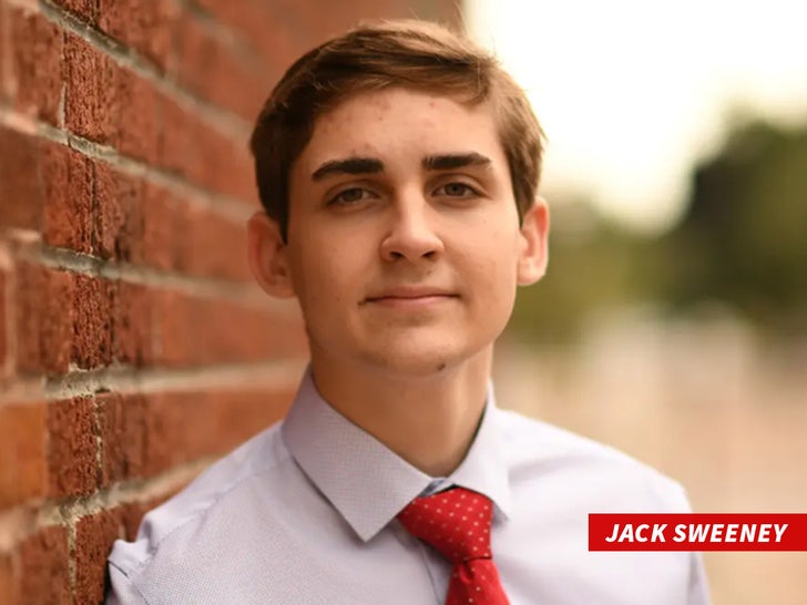 Jack Sweeney in a shirt and tie standing against a brick wall.
