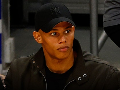 David Andrew Armstrong is seen looking out during an event. He's wearing a black jacket, as well as a matching t-shirt and Yankees cap.