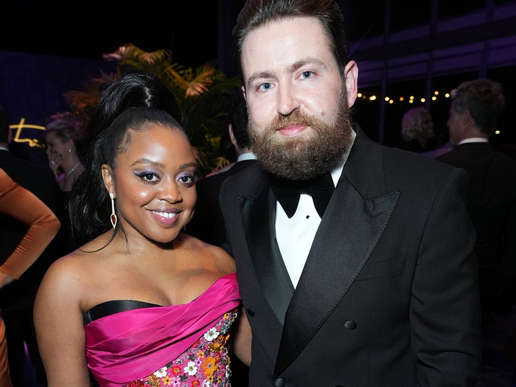 Quinta Brunson and her husband Kevin Anik are seen at what appears to be an awards show. She's wearing a multicolored dress, while he's wearing a black tuxedo.