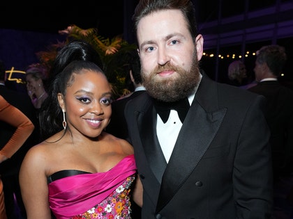 Quinta Brunson and her husband Kevin Anik are seen at what appears to be an awards show. She's wearing a multicolored dress, while he's wearing a black tuxedo.
