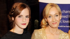 Emma Watson is seen while standing next to J.K. Rowling. Emma's wearing a black top, while J.K.'s wearing a gold dress and a flower-shaped pin.